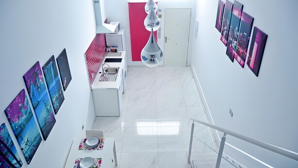 A modern interior with a staircase, a kitchen area, and a dining space with artwork on the walls. - Studio Apartment 'Ofis - Estudio Morado' with Wi-Fi and Air Conditioning (Conil de la Frontera)