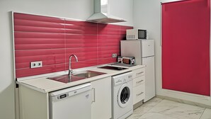 A compact kitchen with a dishwasher, washing machine, microwave, and a red tiled backsplash. - Studio Apartment 'Ofis - Estudio Morado' with Wi-Fi and Air Conditioning (Conil de la Frontera)