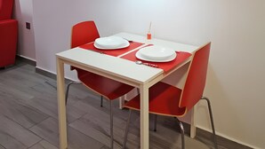 A dining area with a white table and red chairs, a red pendant light, and an air conditioning unit on the wall. - Studio Apartment 'Ofis - Estudio Rojo' with Wi-Fi and Air Conditioning (Conil de la Frontera)