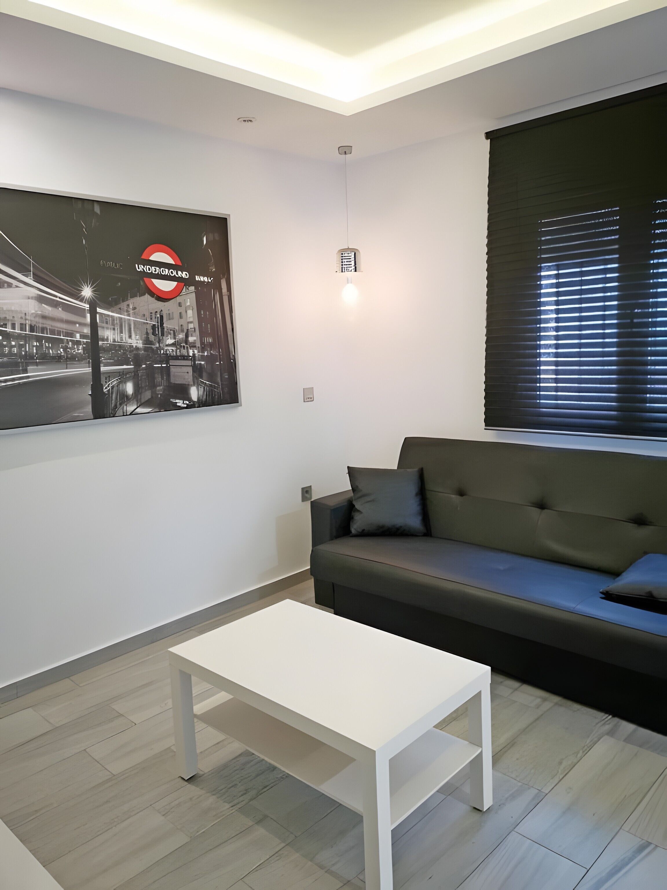 Ein modernes Wohnzimmer mit einem weißen Couchtisch, einem grauen Sofa und einem großen Poster der Londoner U-Bahn.