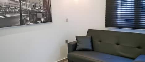 A modern living room with a white coffee table, a grey sofa, and a large poster of the London Underground.