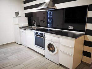 A compact kitchen with a dishwasher, oven, and built-in washing machine. - Studio Apartment 'Ofis - Estudio Negro' with Wi-Fi and Air Conditioning (Conil de la Frontera)