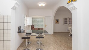 A kitchen with a bar area, a tiled backsplash, and a dining area with a table and chairs. - 4-Bedroom Villa El Romero—Private Pool, BBQ & Relaxation (Arucas)
