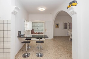A kitchen with a bar area, a tiled backsplash, and a dining area with a table and chairs. - 4-Bedroom Villa El Romero—Private Pool, BBQ & Relaxation (Arucas)