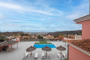 A rooftop pool area with lounge chairs and umbrellas, overlooking a coastal town. - 4-Bedroom Villa El Romero—Private Pool, BBQ & Relaxation (Arucas)