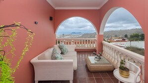 A balcony with a white sofa, a small table, and a potted plant. - 4-Bedroom Villa El Romero—Private Pool, BBQ & Relaxation (Arucas)
