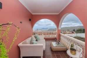 A balcony with a white sofa, a small table, and a potted plant. - 4-Bedroom Villa El Romero—Private Pool, BBQ & Relaxation (Arucas)