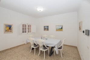 A dining room with a round table, white chairs, and artwork on the walls. - 4-Bedroom Villa El Romero—Private Pool, BBQ & Relaxation (Arucas)