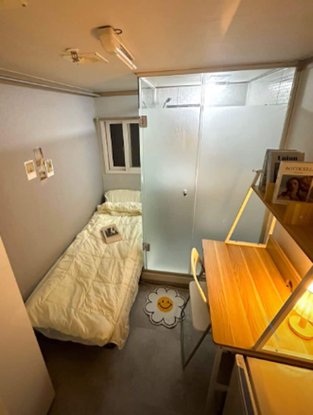 A small, compact room with a single bed, a desk with a chair, and a wardrobe.