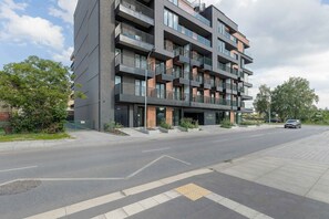 Ein mehrgeschossiges Wohngebäude mit Balkonen, einem verschlossenen Eingangsbereich und einer freien Straße davor.