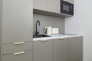 Eine moderne Küche mit grauen Schränken, einer schwarzen Mikrowelle, einem Spülbecken und einer Bosch-Kaffeemaschine.