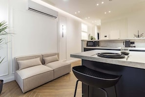 A modern kitchen with a built-in island, a sofa, and a bar stool. - [Lungolago] Nuovo Bilocale 5 (Como)