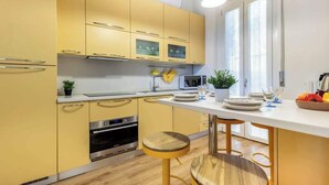 A modern kitchen with yellow cabinets, a microwave, and a wooden stool. - silk and sunset - city and lake view (Como)