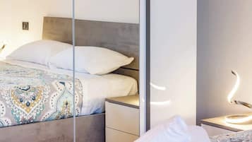 Een moderne slaapkamer met een bed, nachtkastje en spiegel.
