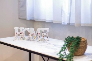 Ein Tisch mit dekorativen Buchstaben, die 'HOME' bilden, und einer Pflanze in der Ecke.