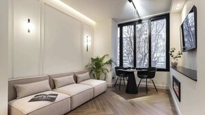 En moderne stue med en sofa, et spisebord med stole og store vinduer.