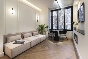 A modern living room with a sofa, a dining table with chairs, and large windows. - [Lungolago] Nuovo Bilocale 3 (Como)