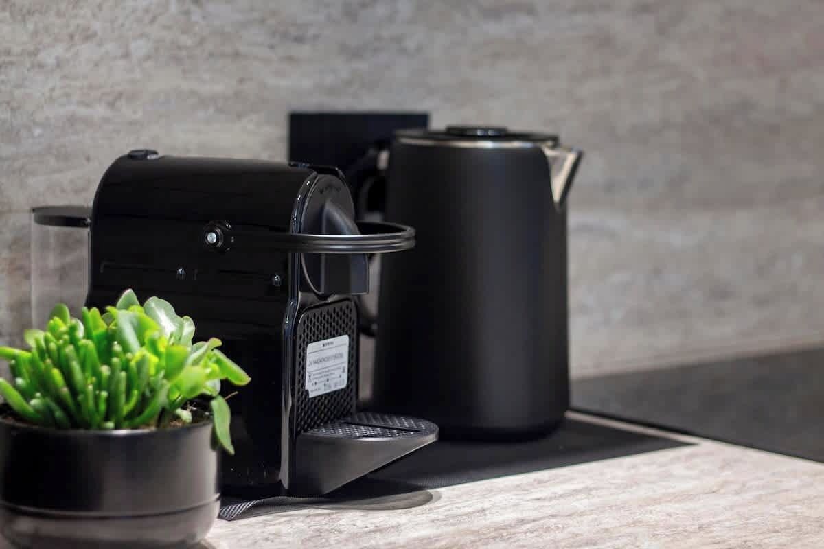 Una cucina con una macchina da caffè, un bollitore e una pianta in vaso sul bancone.