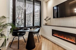 A modern interior with a dining table, chairs, a flat-screen TV, and a fireplace. - [Lungolago] Nuovo Bilocale 3 (Como)