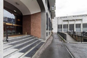A building with a staircase leading to a covered entrance, a balcony with a railing, and a sign that reads 'STADIO G.SINIGAGLIA'. - [Lungolago] Nuovo Bilocale 3 (Como)