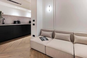 A modern kitchen with a built-in stove, dark cabinets, and a herringbone wood floor. - [Lungolago] Nuovo Bilocale 3 (Como)