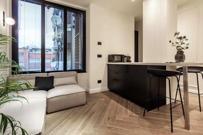 Eine moderne Küche mit schwarzer Arbeitsplatte, weißer Rückwand und einem Fenster mit Jalousien.