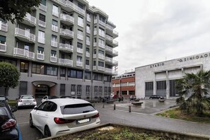 A multi-story building with balconies, a parking area, and a sign that reads 'STADIO G.SINIGAGI'. - [Lungolago] Nuovo Bilocale 1 (Como)