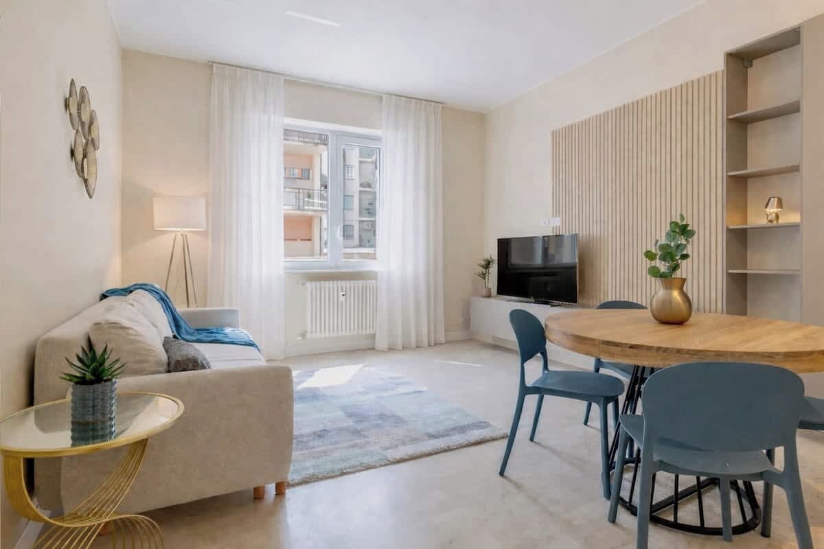 Un salon moderne comprenant un canapé, une table basse, un téléviseur et un coin repas avec des chaises et une table.