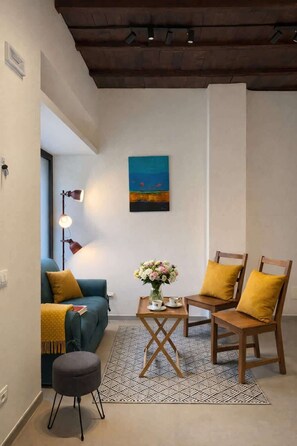 A modern living room with a blue sofa, wooden chairs, a coffee table with flowers, and a painting on the wall. - [Borgovico] Modern Romantic Como Central Apt (Como)