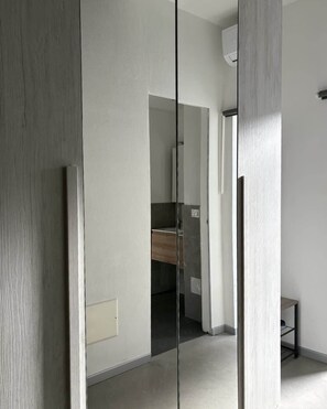 A modern interior with a minimalist design, featuring a wooden floor, a white wall, and a glass partition. - [Borgovico] Modern Romantic Como Central Apt (Como)