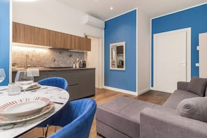 A modern living space with a dining area, a kitchen, and a seating area. - [Lungolago] Nuovo Bilocale 6 (Como)