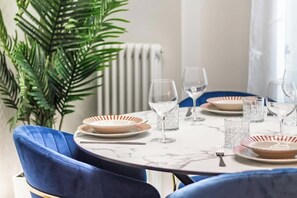 A dining table set with plates, glasses, and cutlery, surrounded by blue upholstered chairs. - [Lungolago] Nuovo Bilocale 6 (Como)