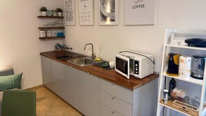 A kitchen with a microwave, coffee maker, and shelves with kitchenware.