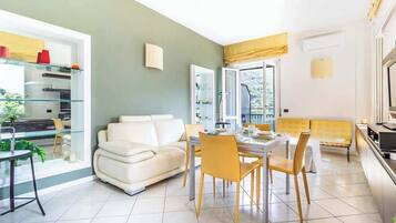 A modern living room with a dining area, a sofa, and a glass coffee table.
