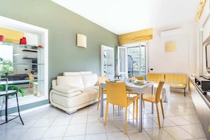 A modern living room with a dining area, a sofa, and a glass coffee table.