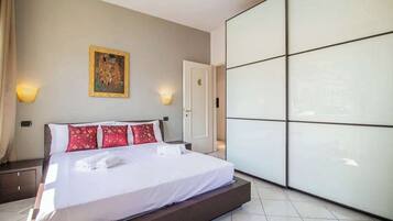 A hotel room with a bed, a wall-mounted painting, and a wardrobe with mirrored doors.