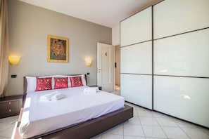 A hotel room with a bed, a wall-mounted painting, and a wardrobe with mirrored doors.