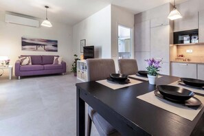 A modern living space with a sofa, dining table, and kitchen area. - La Bréva - Central Apartment [1 minuto dal centro] (Como)