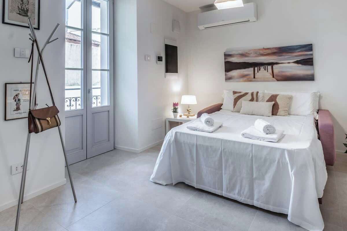 Une chambre d’hôtel avec un lit, une table de chevet avec une lampe, un tableau au mur et une fenêtre.
