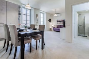 A modern kitchen with a dining table and chairs, a sofa, and a shower area. - La Bréva - Central Apartment [1 minuto dal centro] (Como)
