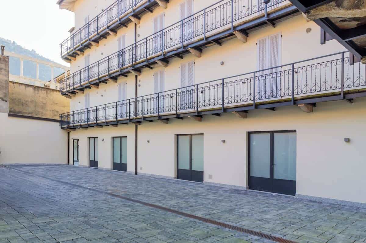 Un immeuble à plusieurs étages doté de balcons, de grandes fenêtres et d’une cour dallée.