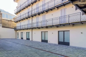 Ein mehrstöckiges Gebäude mit Balkonen, großen Fenstern und einem gepflasterten Innenhof.