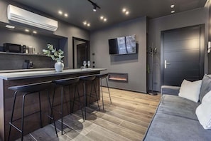 A modern kitchen with a bar area, a flat-screen TV, and a fireplace. - [Lungolago] Nuovo Bilocale 2 (Como)