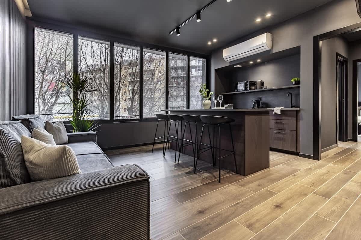 A modern kitchen with a bar area, large windows, and a seating area with a sofa and chairs.