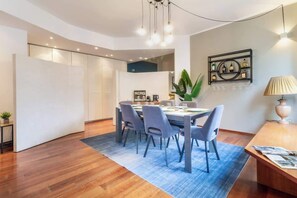 A modern dining area with a wooden table, grey chairs, and a blue rug. - [Duomo] Como Central Square (Como)