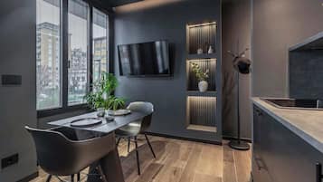 Une cuisine moderne dotée d’un téléviseur encastré, d’un coin repas avec une table et des chaises, et d’une plante.