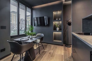 Une cuisine moderne dotée d’un téléviseur encastré, d’un coin repas avec une table et des chaises, et d’une plante.