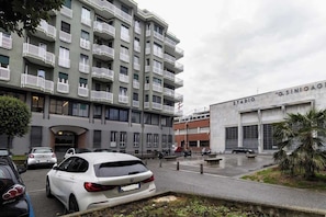 Un immeuble résidentiel à plusieurs étages, doté de balcons et d’un espace de stationnement.