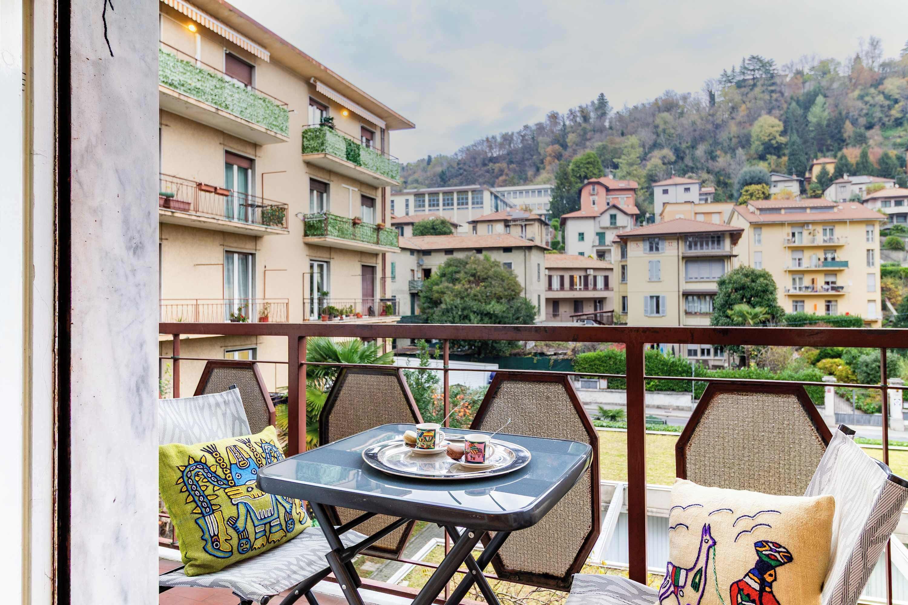 Ein Balkon mit Tisch für zwei Personen, Blick auf ein Wohngebiet mit mehreren Gebäuden.