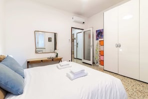 Quarto de hotel com cama, mesa de cabeceira, espelho, guarda-roupa e porta do banheiro.